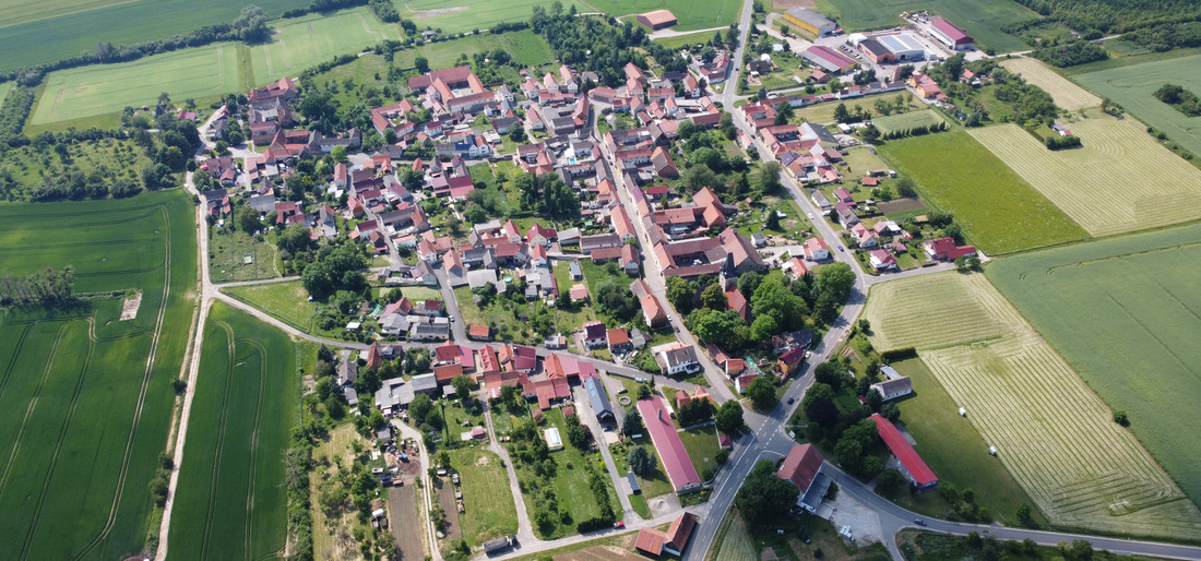 Das Helbedündorf von oben - ein Dorf mit vielen roten Dächern zwischen grünen Feldern