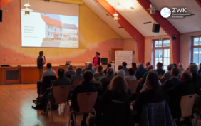 Mehere Dutzend Menschen sitzen in Romrod in einem Saal mit Spitzdach und hören der Veranstaltung Energetisch Sanieren im Bestand zu.