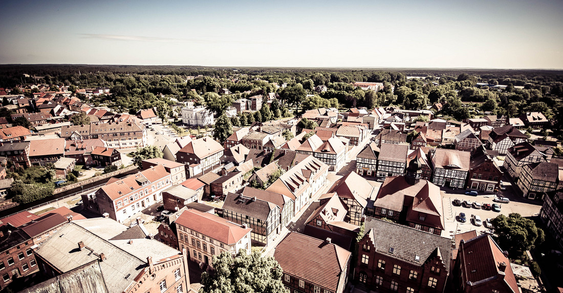 Eine kleine Stadt mit vielen roten Ziegeldächern und einigen Fachwerkhäusern umgeben von Bäumen.