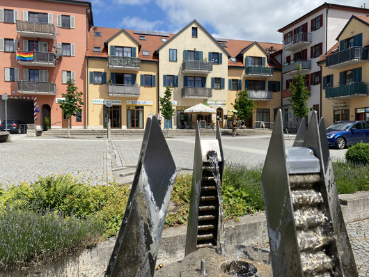 Häuser um einen Marktplatz mit Wasserspiel