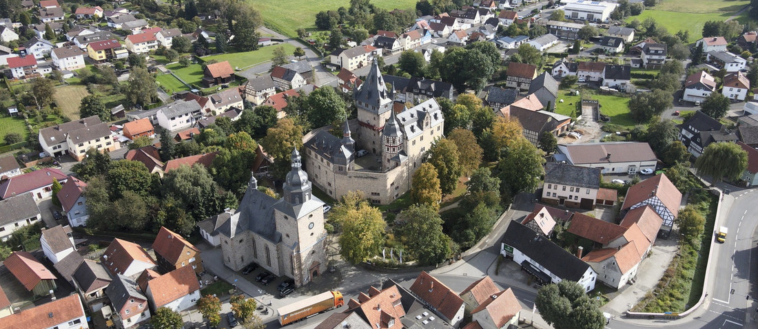 Luftbild von einem Dorf mit einem Schloss im Zentrum