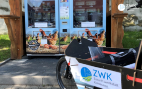 Ein Lastenrad im ZWK Design vor einem Regiomaten, einem Lebensmittelautomaten für regionale Produkte