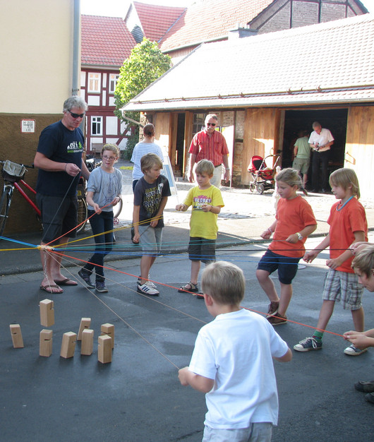 Kinder und Erwachsene spielen draußen ein Geschicklichkeitsspiel