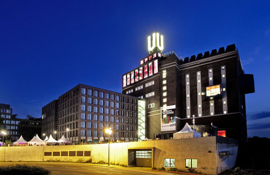 Industriegebäude mit einem leuchtenden U auf dem Dach, bei Nacht.