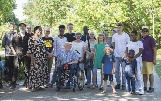 Ein Gruppe Menschen unterschiedlichen Alters und unterschiedlicher Hautfarbe lächeln gemeinsam in die Kamera.