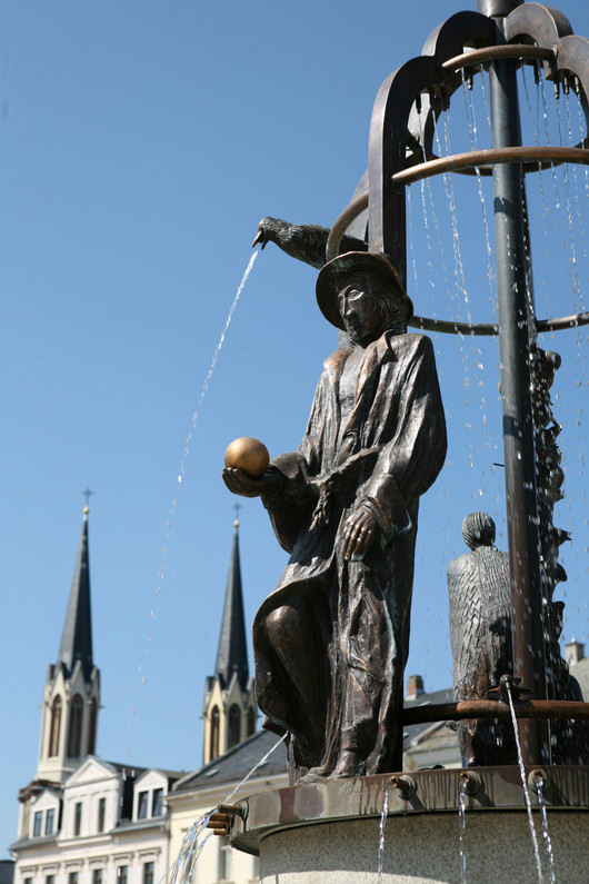 Brunnenstatur eines Mannes mit goldener Kugel und Hut