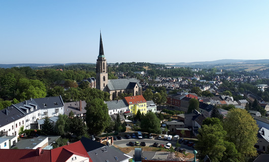 Ein Dorf mit Kirchturm und grünem Umland.