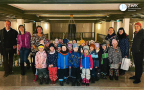 Eine Gruppe Kinder und sechs Erwachsene lachen die Kamera.