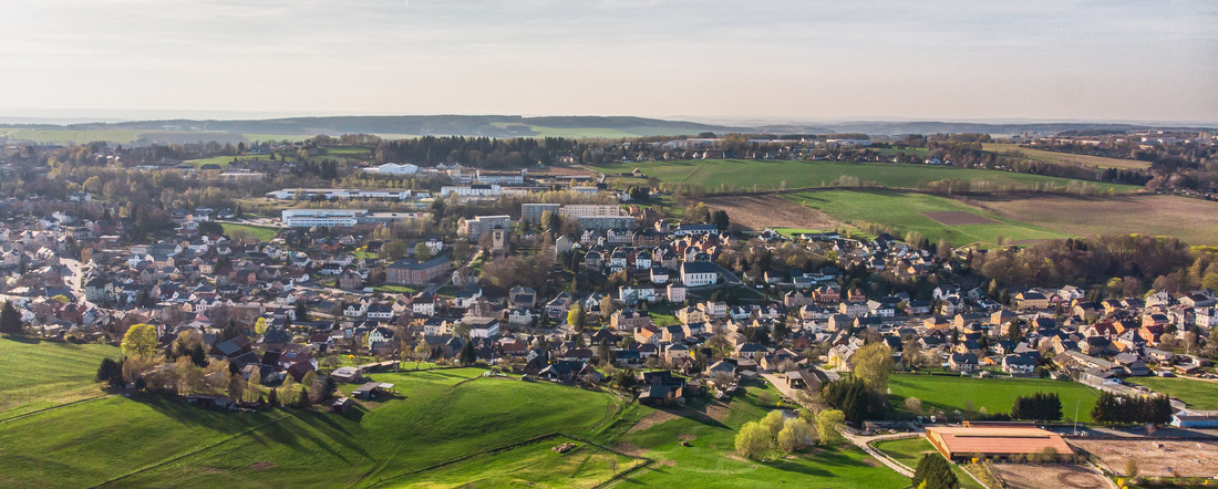 Gründe Wiesen und Felder und eine Gemeinde mit vielen Häusern und einem Pferdehof.