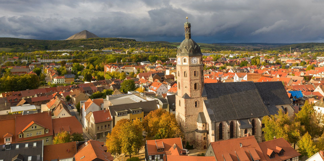 Eine Stadt mit vielen roten Ziegeldächern und einer Kirche mit rundem Turm im Zentrum.