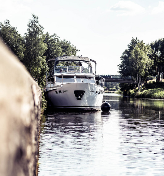 Ein Fluss aus der Wasserperspektive. Links die Kielmauer und geradeaus ein weißes Boot.