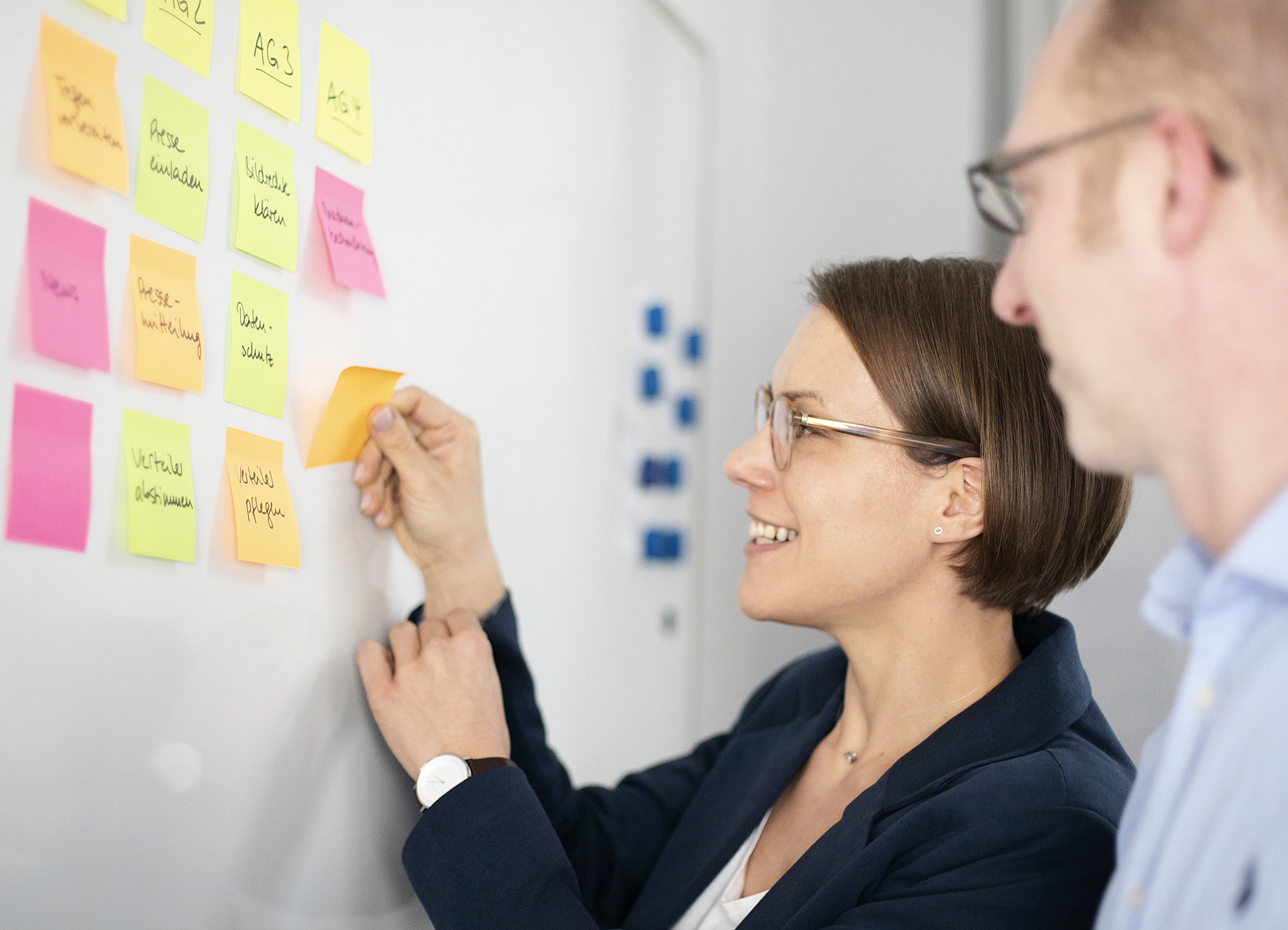 Eine Beraterin und ein Berater stehen am Whiteboard.