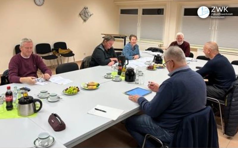 Teilnehmende der AG Wohnen sitzen rund um einen Tisch.