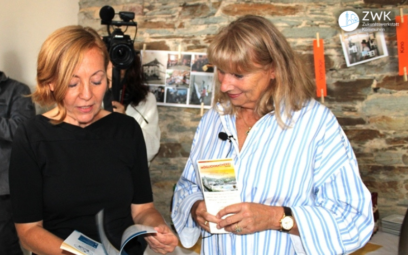 Bianca Jahn und Petra Köpping schauen gemeinsam in eine Broschüre