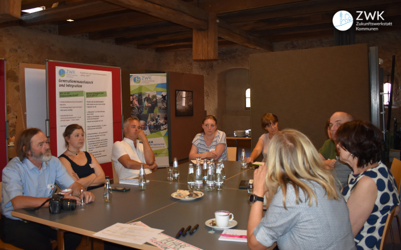 Teilnehmende der dritten Zukunftswerkstatt in Riesa sitzen um einen Tisch und reden.