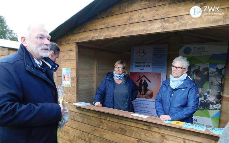 Links Bürgermeister Matthias Schilling, rechts ein Informationsstand zur Zukunftswerkstatt Kommunen mit zwei Frauen